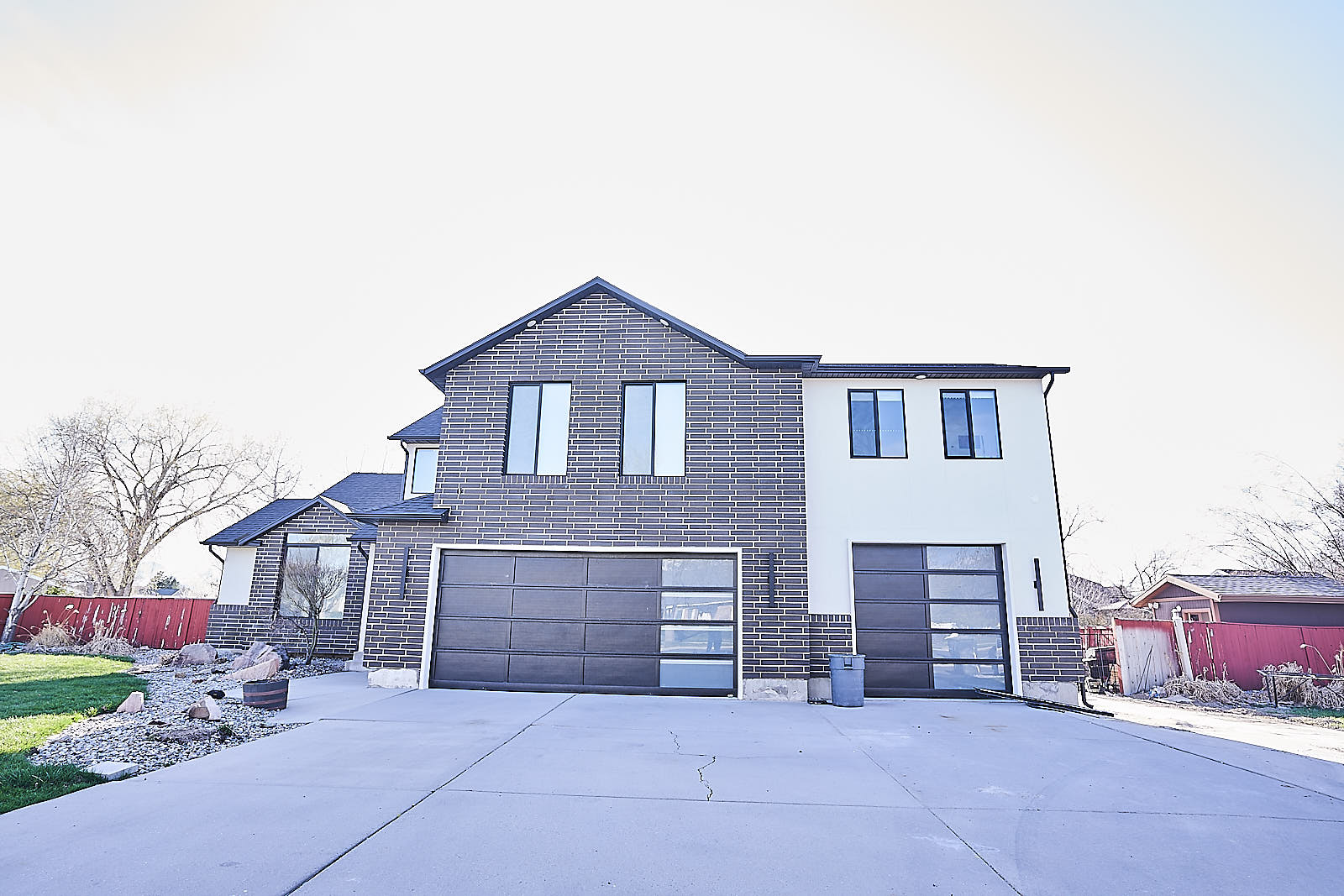 South Jordan project: Completed home addition exterior featuring modern dark brick, light siding, and three-car garage (Photo 1/29)