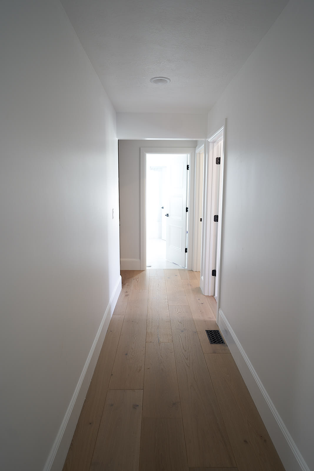 South Jordan project: Clean white hallway featuring light oak hardwood flooring and modern white doors (Photo 21/29)