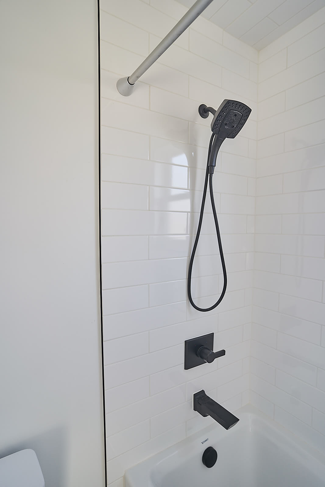 South Jordan project: Modern shower detail with vertical white subway tile and matte black shower head (Photo 25/29)